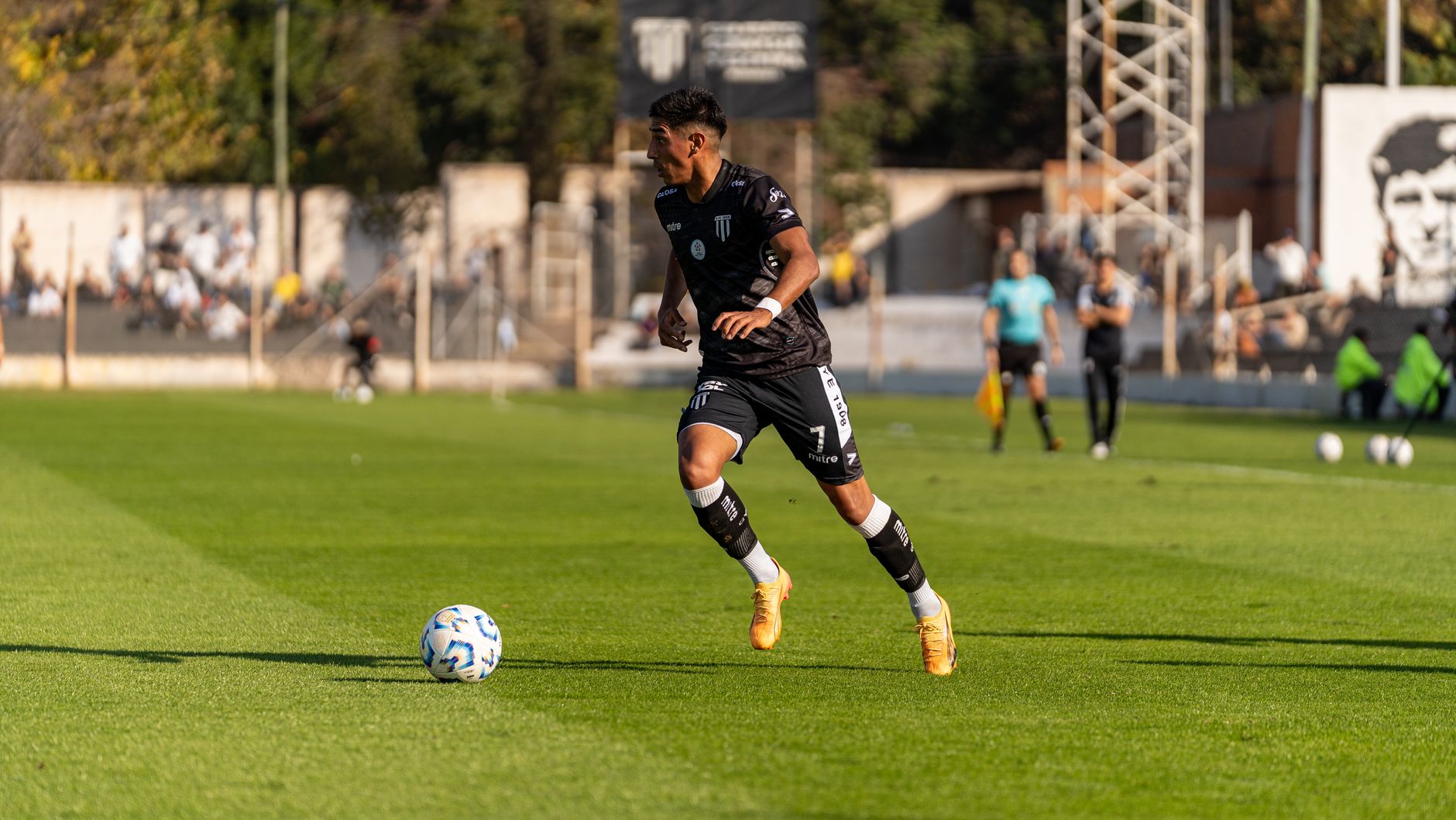 football player dribbling ball on green field stadium
