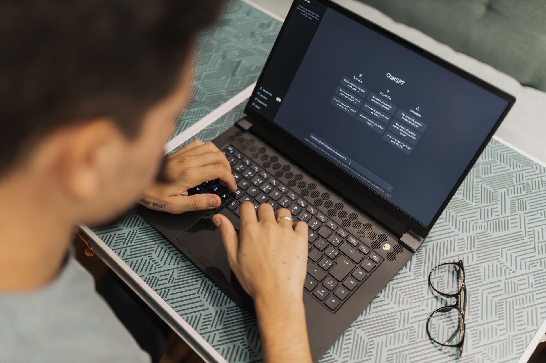 person typing on laptop keyboard with AI chatbot on screen