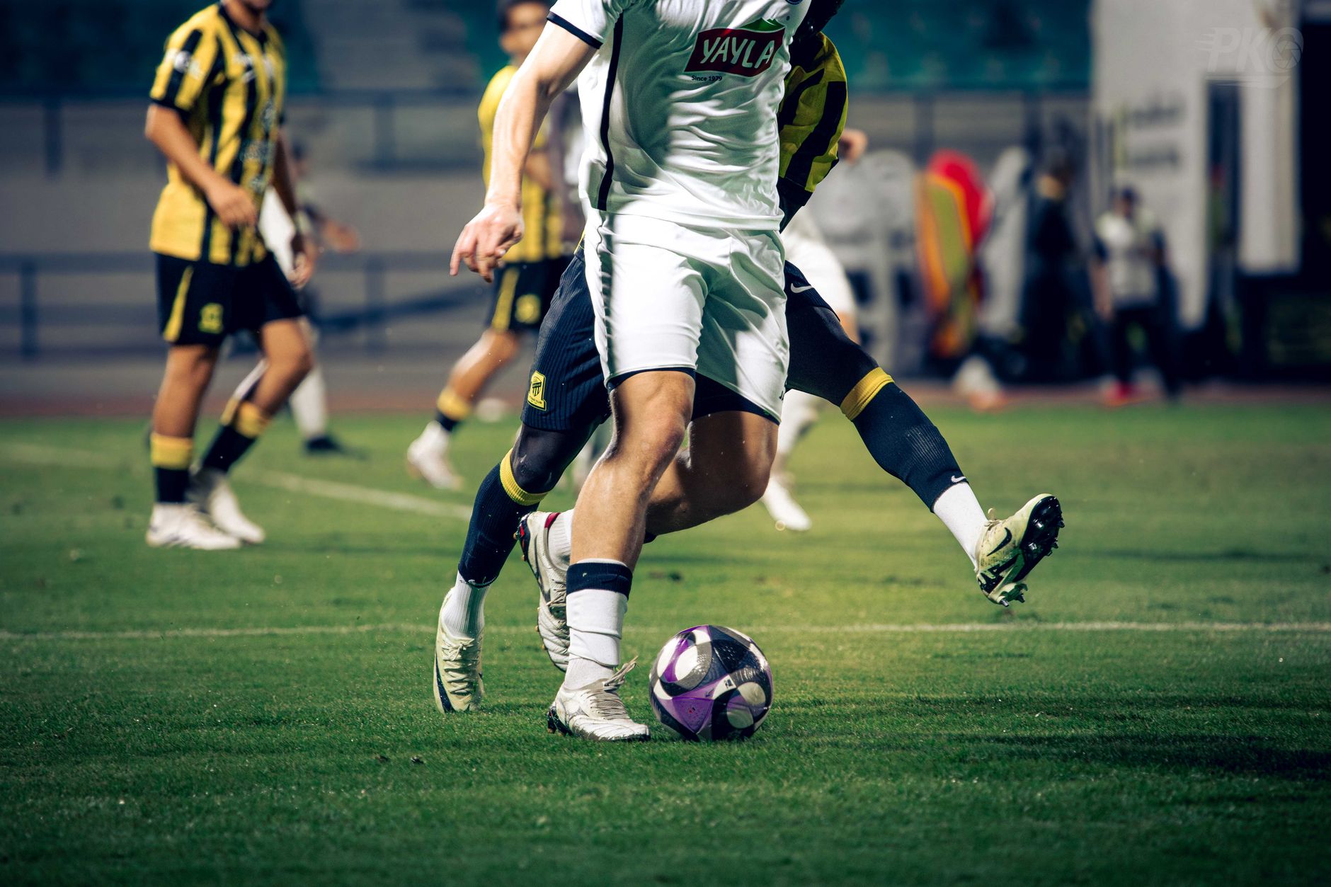 football players competing for ball on field under stadium lights