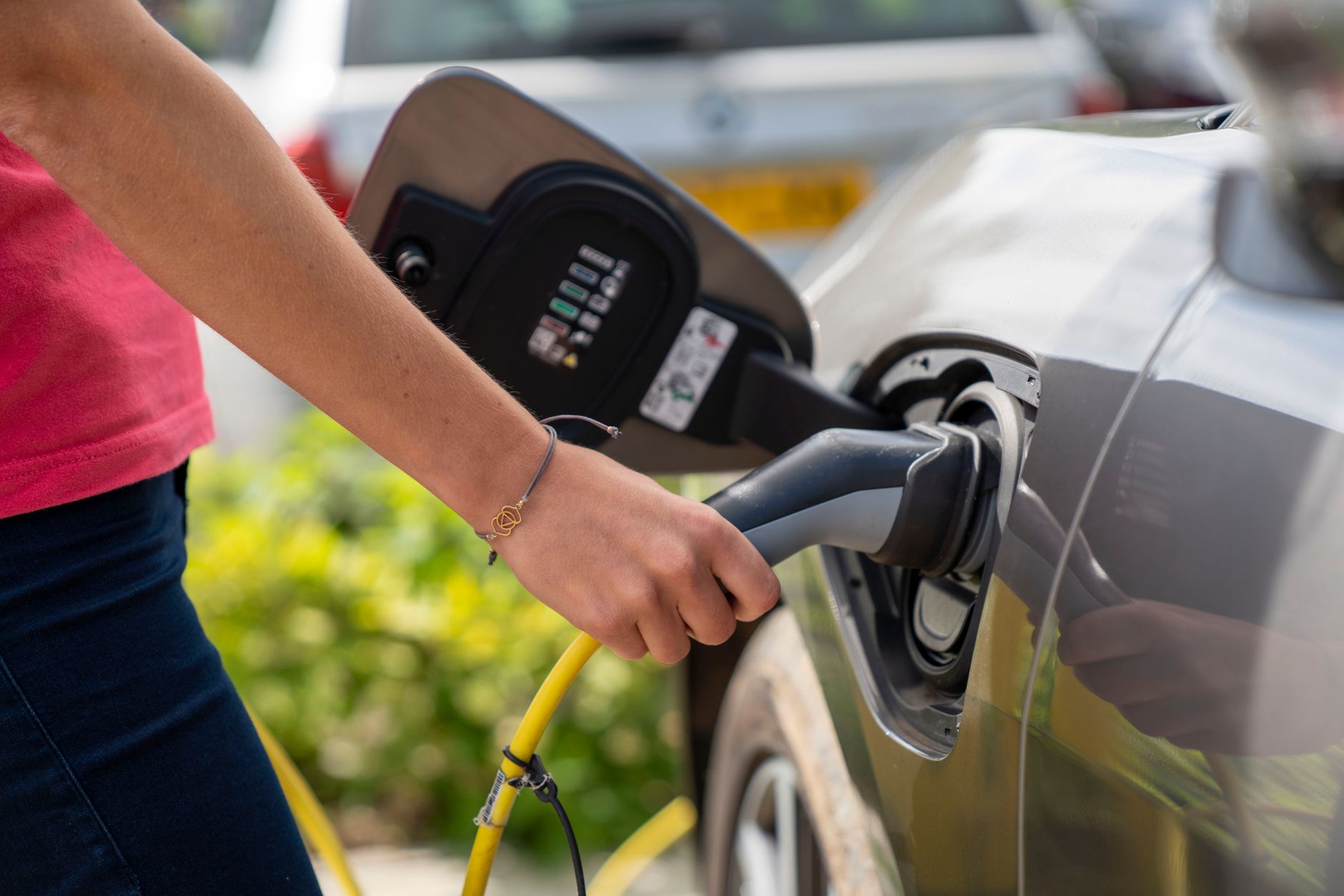 person plugging electric car into charging station