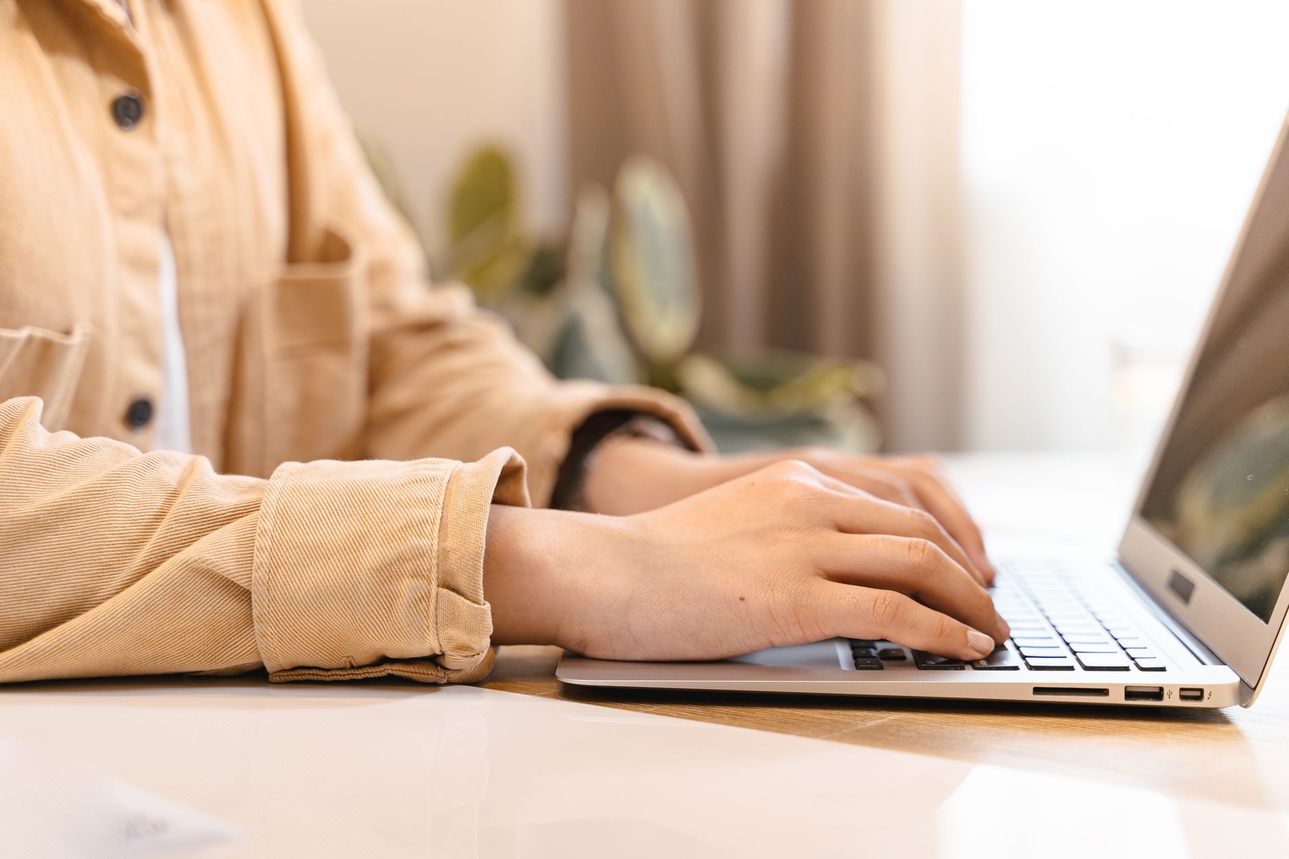 person typing on laptop keyboard in office