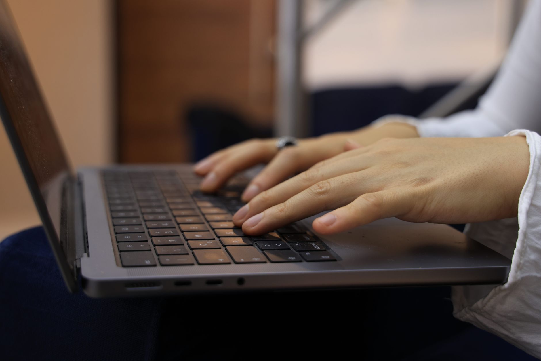 person typing on laptop keyboard in office