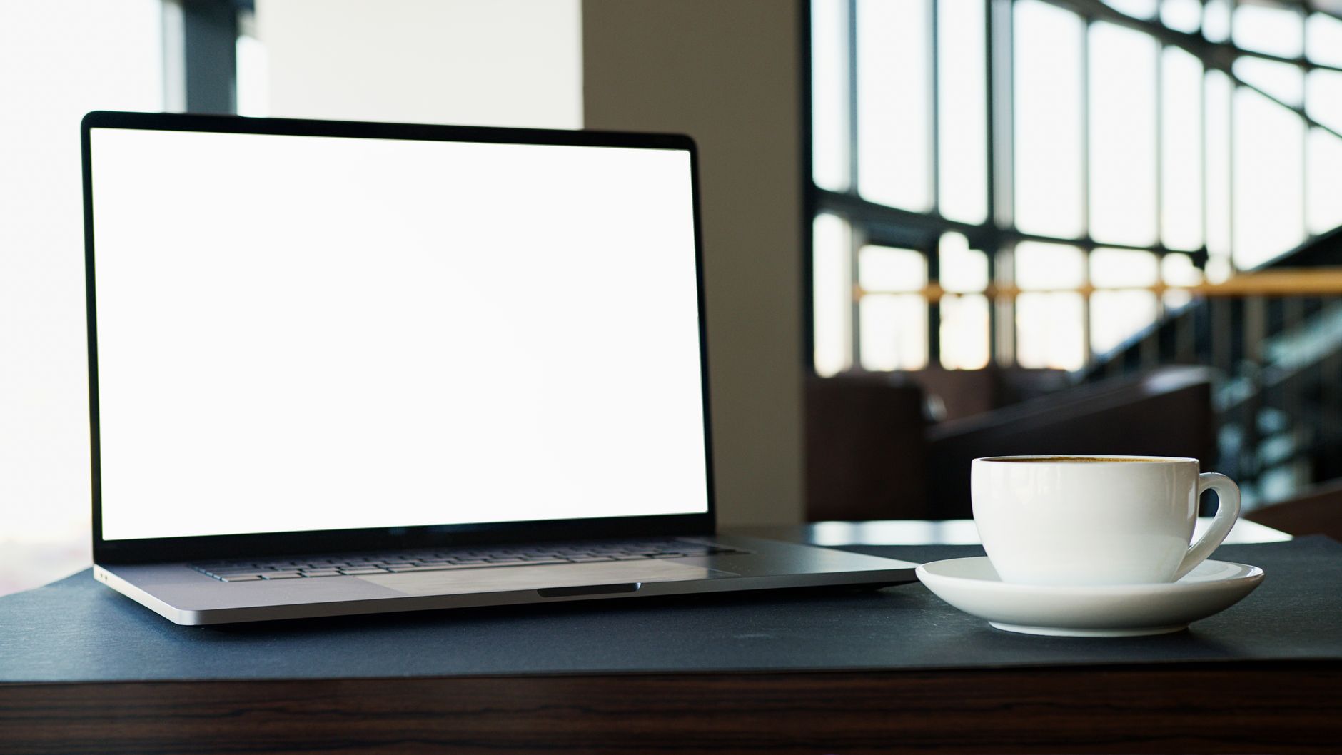 open laptop on wooden desk with coffee mug
