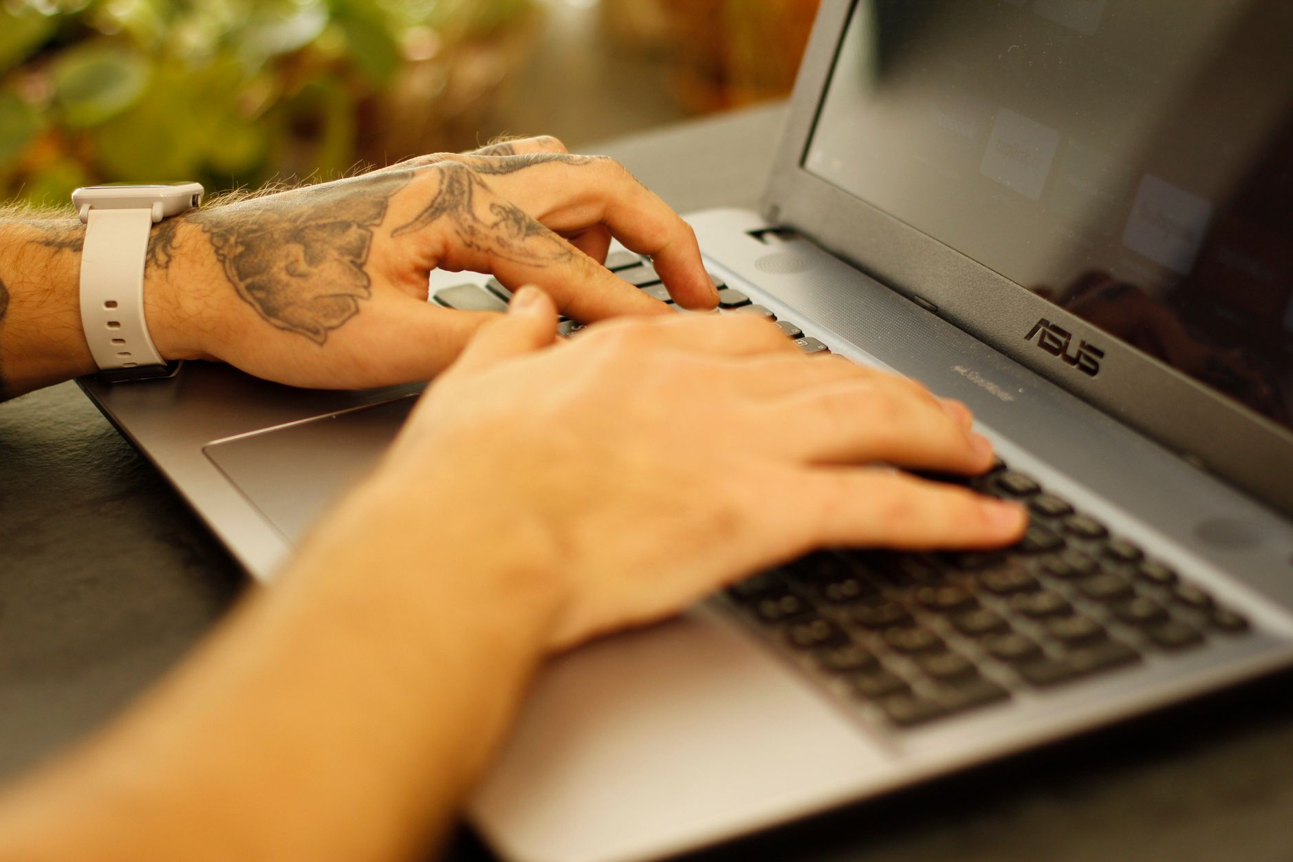 person typing on laptop keyboard in office