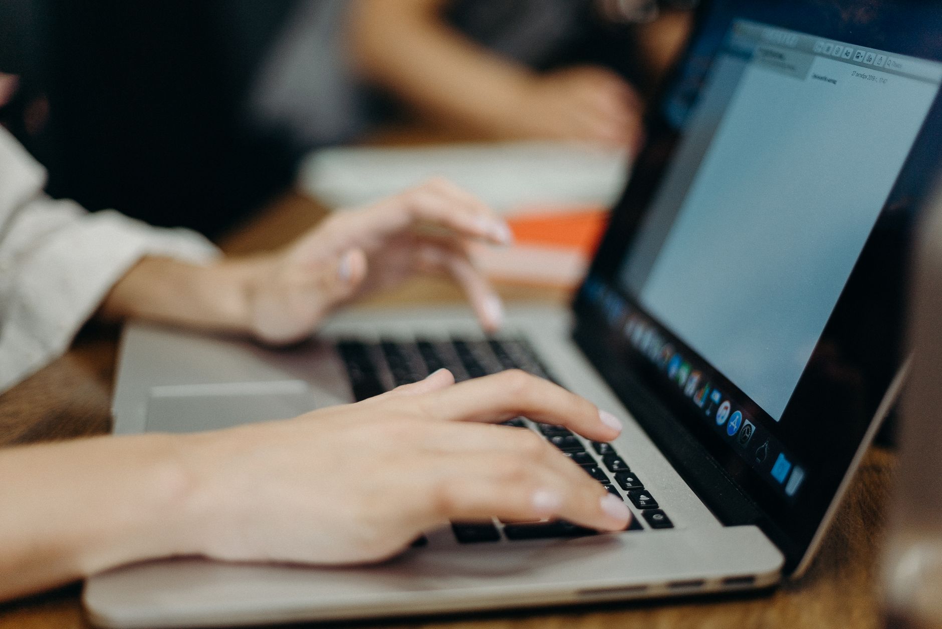 person typing on laptop keyboard in office