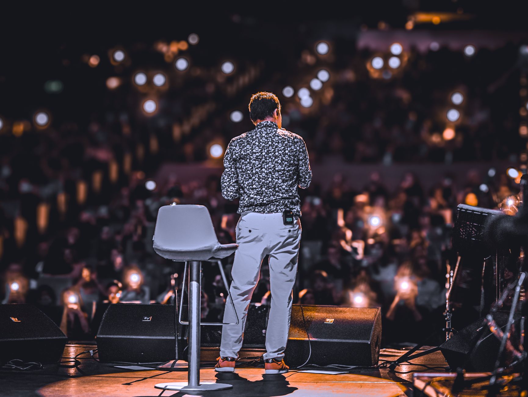 celebrity presenter on stage with microphone lights