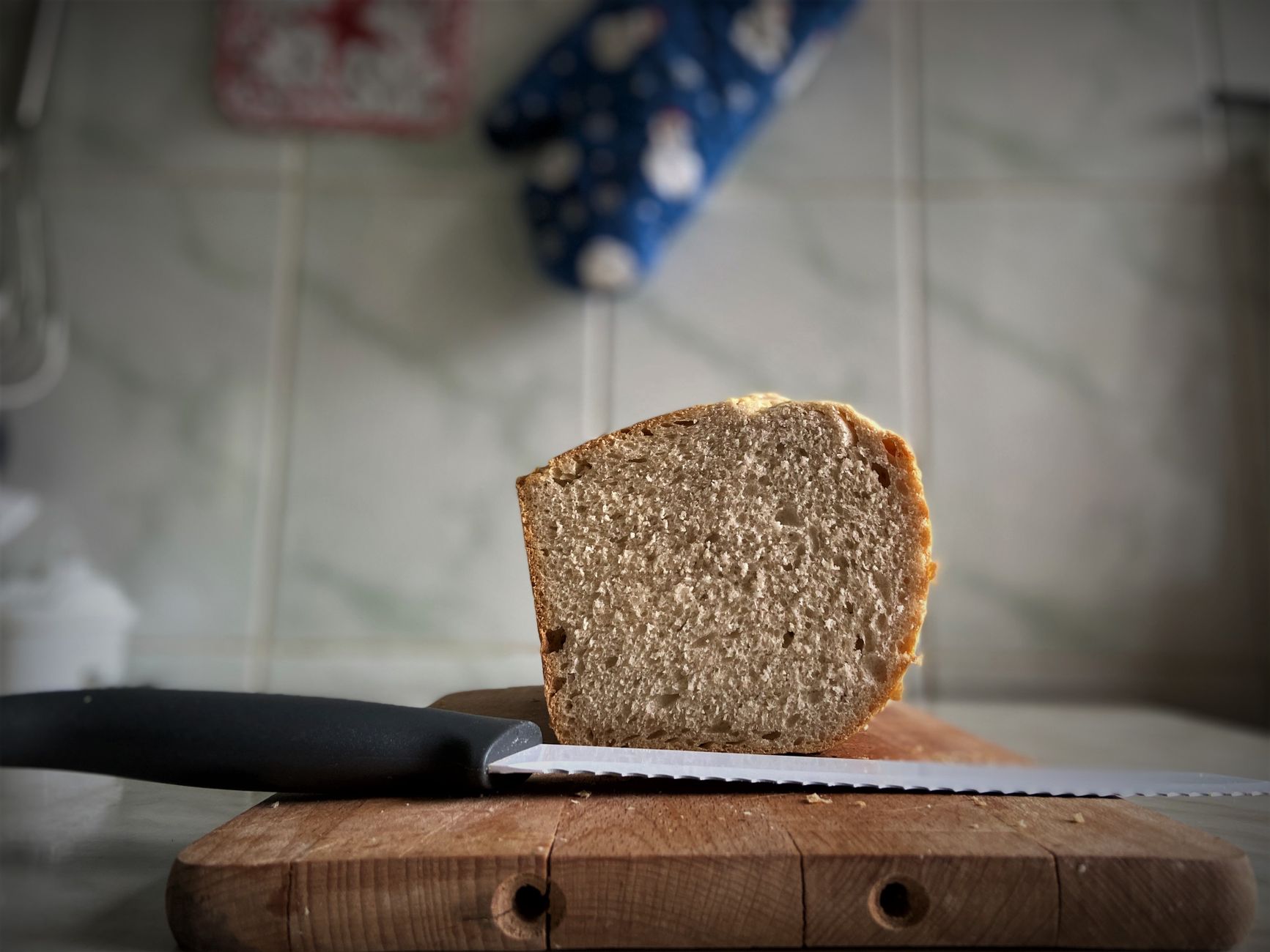 woman slicing fresh sourdough bread on wooden board kitchen