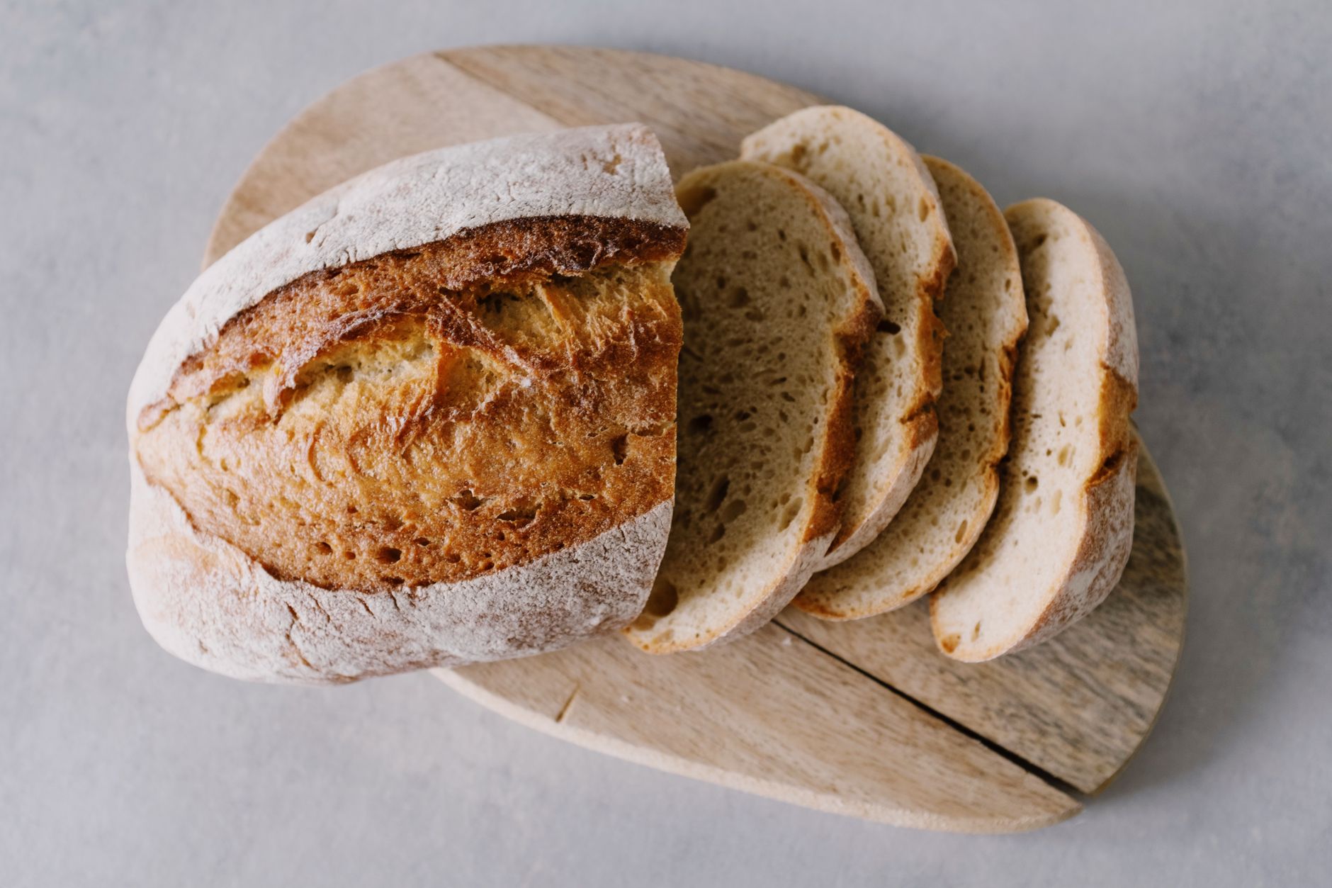 woman slicing sourdough bread on wooden board kitchen