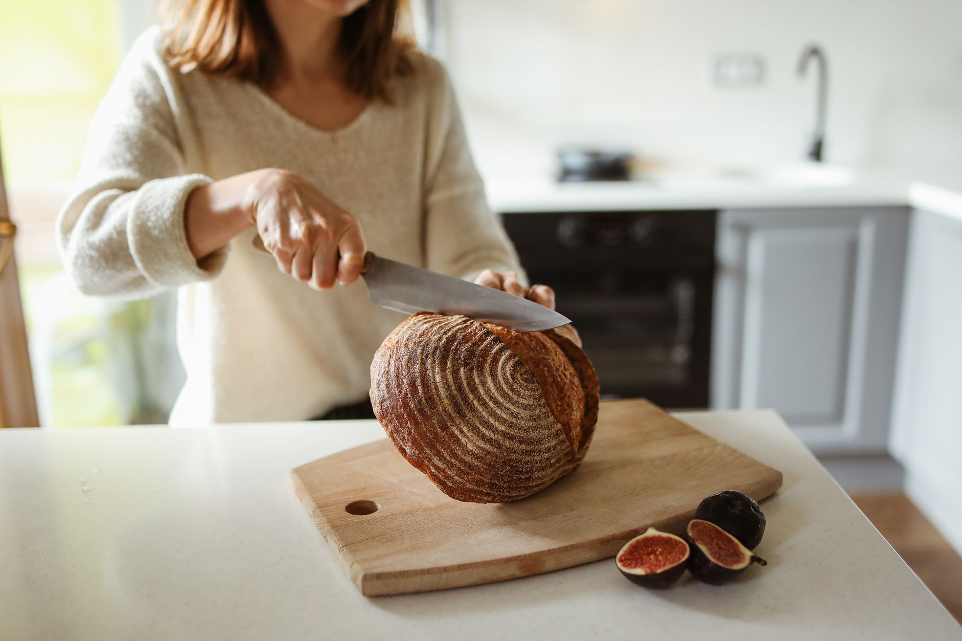 woman slicing fresh sourdough bread kitchen