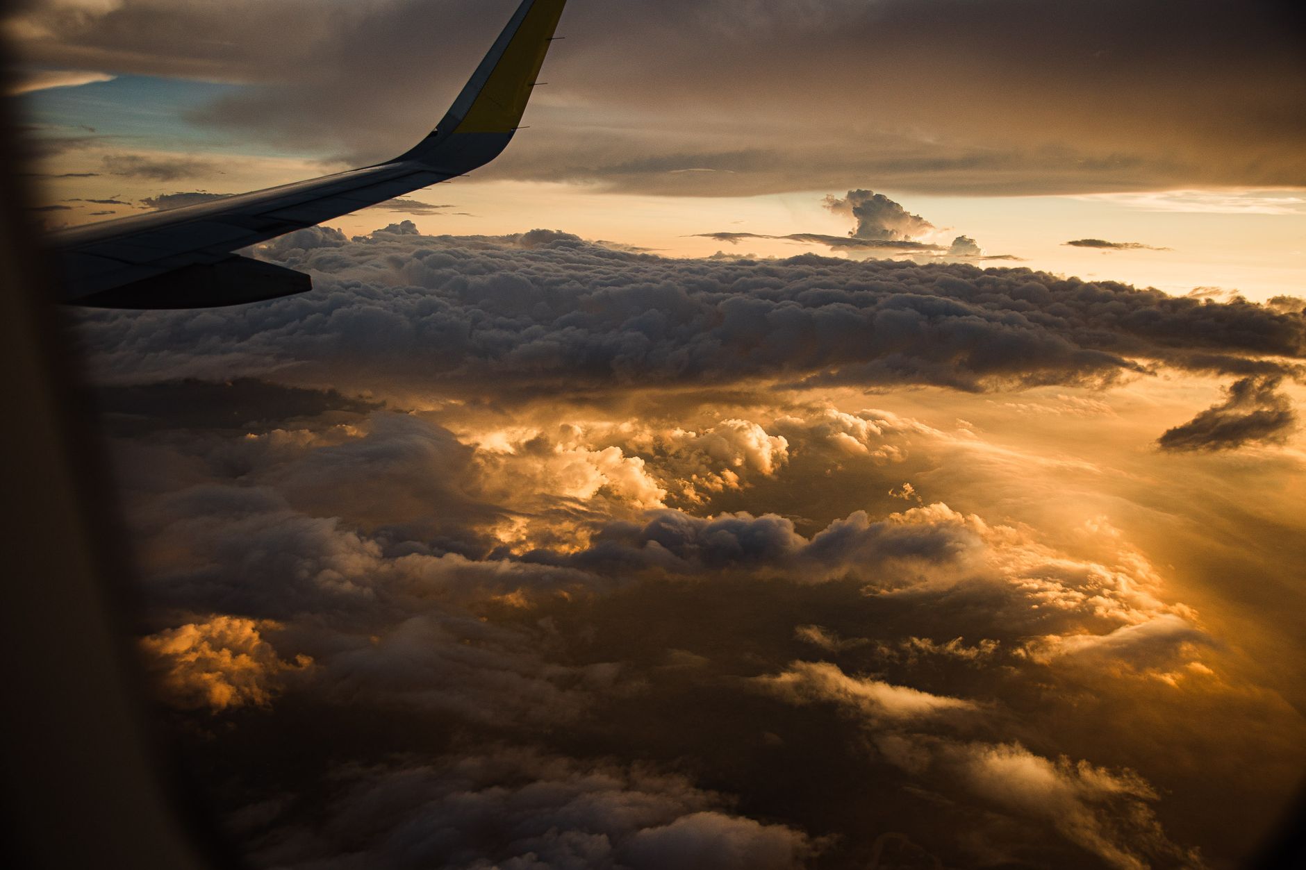 airplane window view above clouds daytime with city lights below