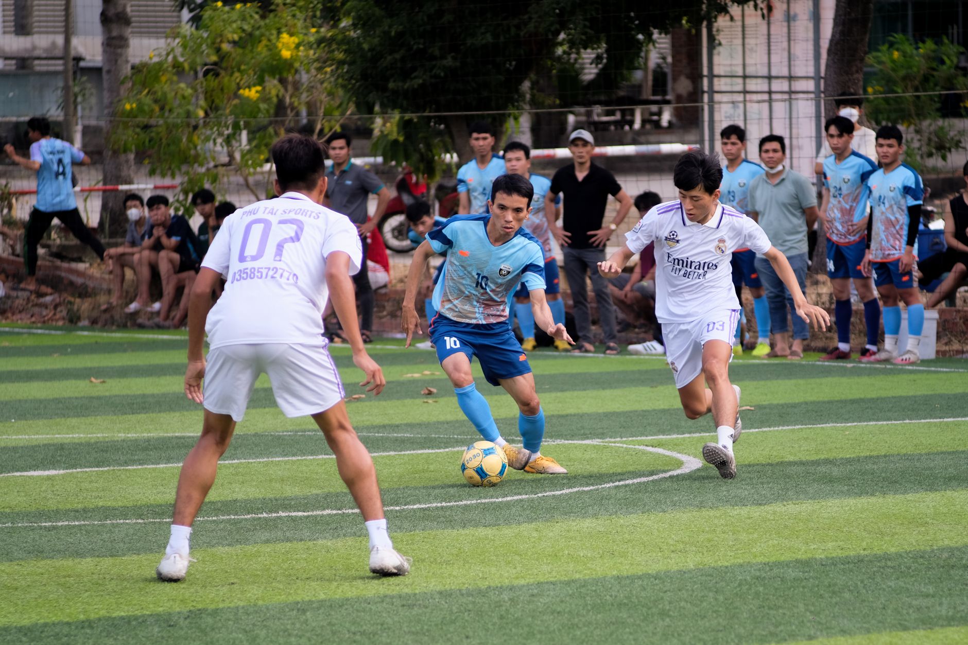 football players competing for ball on green field in daylight