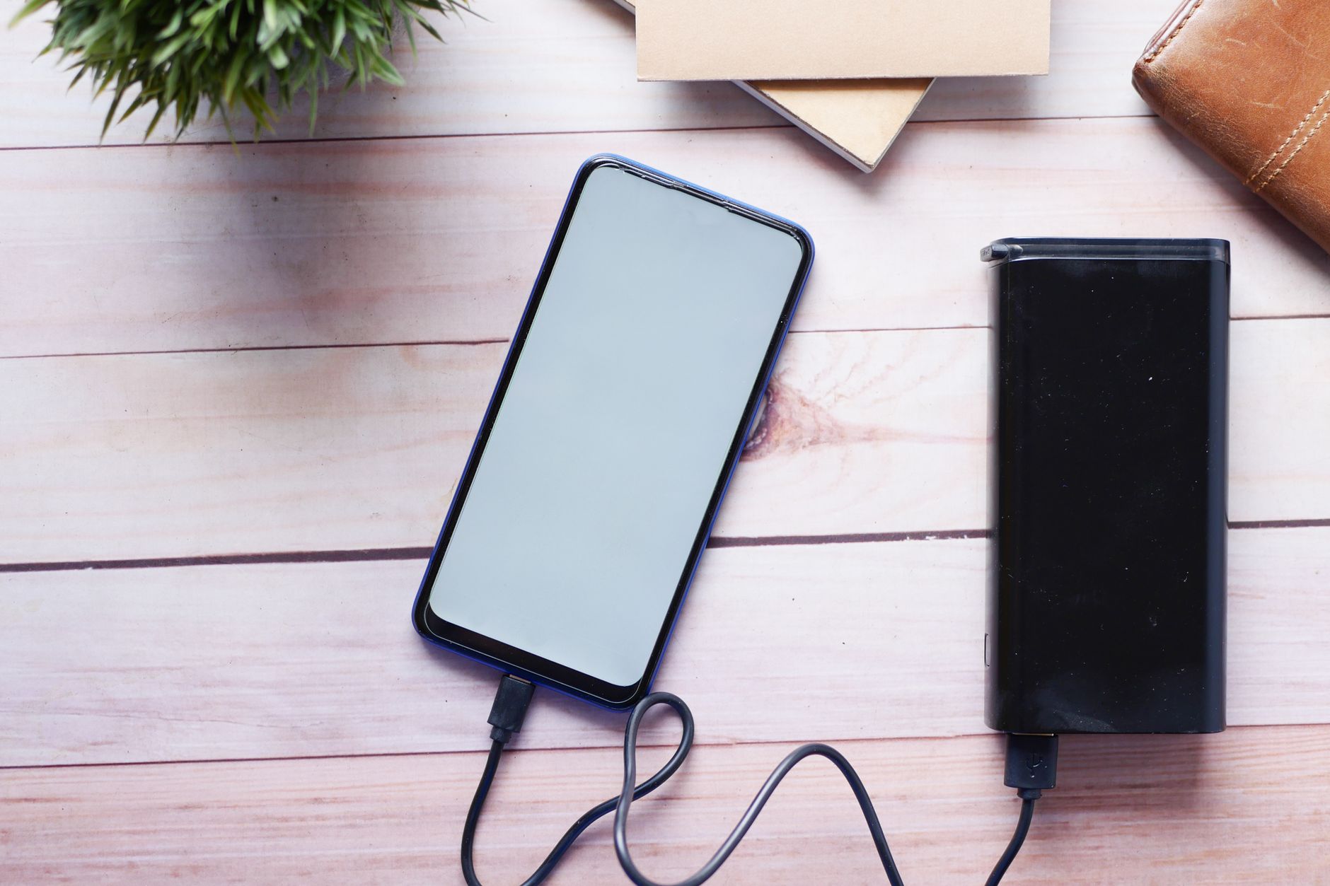 hand holding smartphone charging on desk